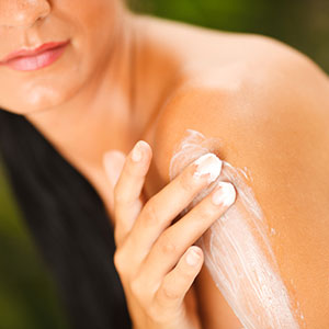 woman applying lotion to her shoulder